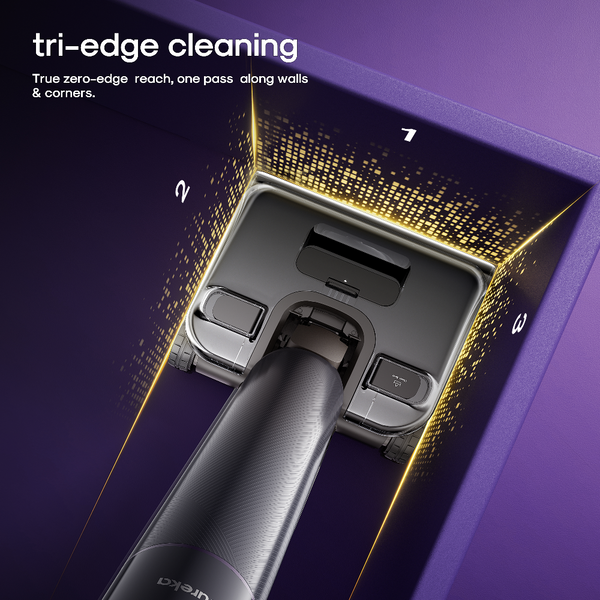 Close-up of a vacuum cleaner head with a dark gray body and metallic silver trim, shown inside a purple room corner with glowing gold light lines and the text 'tri-edge cleaning' and 'True zero-edge reach, one pass along walls & corners.'.